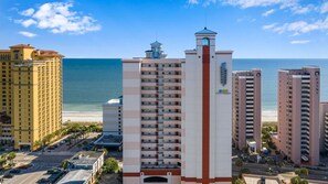 Un hotel de altura con varios pisos, una torre central y vista al océano.
