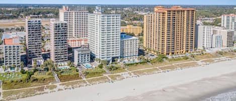 A coastal hotel complex with multiple high-rise buildings, a beach, and a pool area.