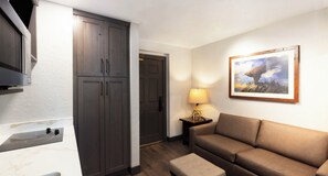 Une chambre d’hôtel équipée d’une kitchenette, d’un canapé, d’une lampe et d’un tableau encadré au mur.