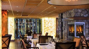 A restaurant interior with a stone wall fireplace, dining tables, chairs, and a wine rack. - Westgate Canyons Ski In/Ski Out,
2 Bd/2Bath, Sleeps 8 w/ full kitchen. 3/21-3/29 (Park City)