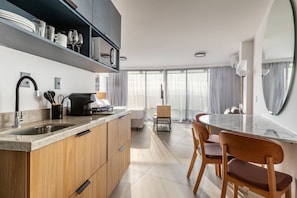 Een moderne keuken met een inbouwoven, een koffieapparaat en een eethoek met een ronde tafel en stoelen.