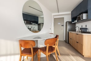 Een moderne keuken met een rond eiland, houten stoelen en inbouwapparatuur.