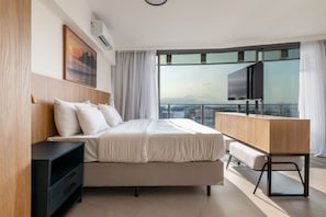 A modern bedroom with a large bed, a desk, and a TV. - Niemeyer 360 (Rio de Janeiro)