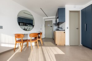 A modern kitchen with a round mirror, wooden chairs, and a built-in microwave. - Niemeyer 360 (Rio de Janeiro)