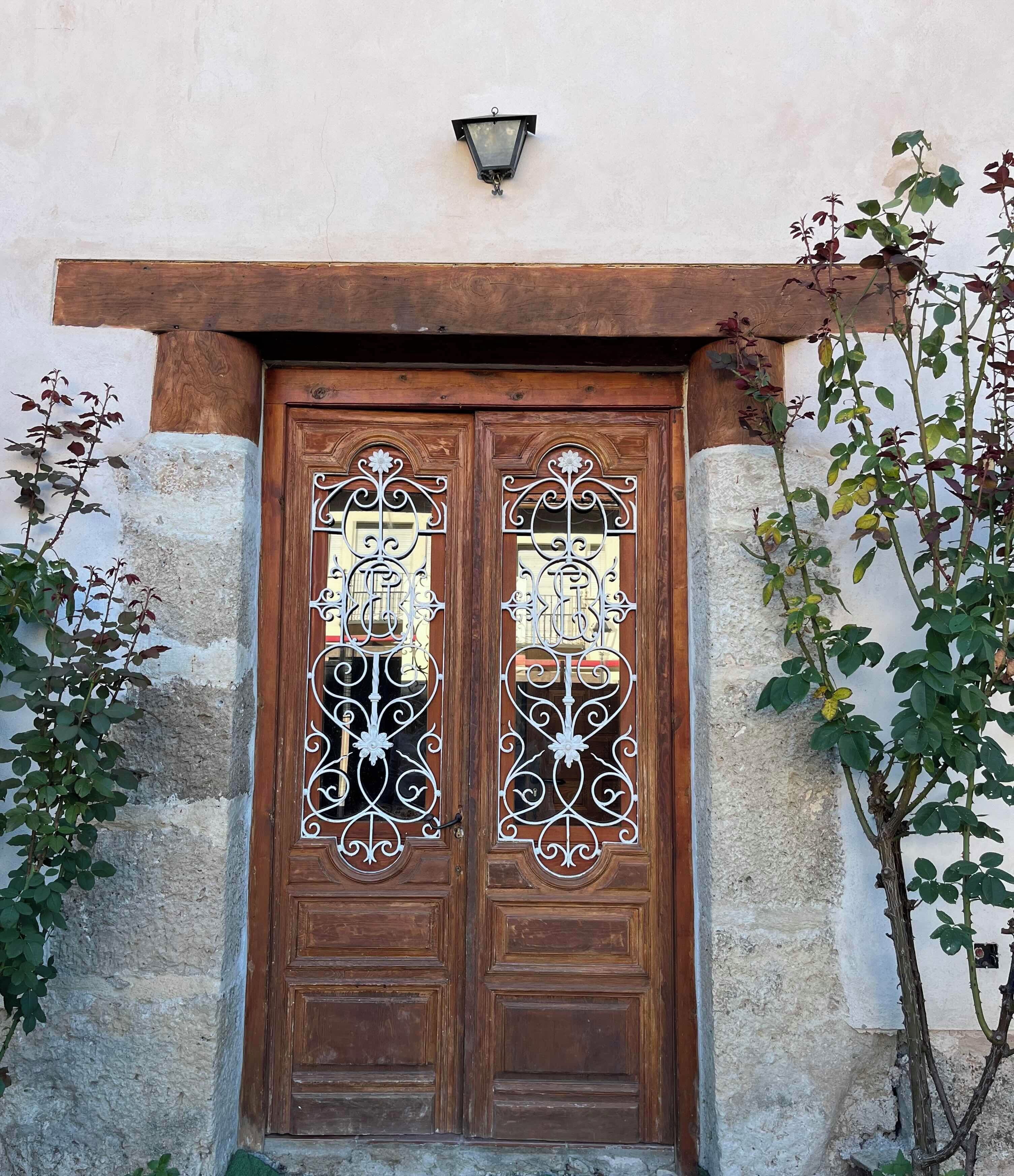 A wooden double door with decorative metalwork and a small wall-mounted light above it.