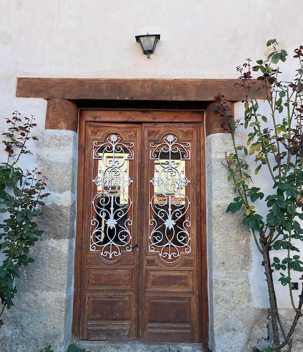 A wooden double door with decorative metalwork and a small wall-mounted light above it.