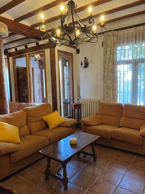 A cozy living room with two sofas, a wooden coffee table, and a chandelier.