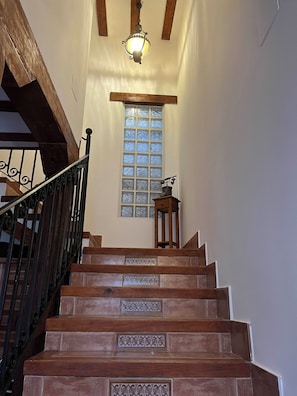A wooden staircase with a handrail, a window with frosted glass, and a hanging light fixture.