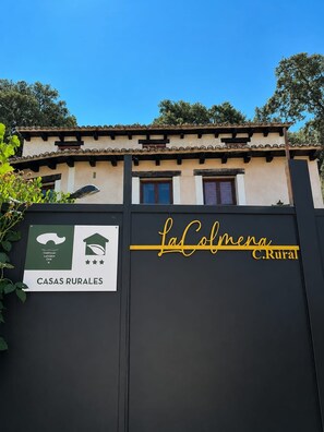 A gated entrance with a sign for 'La Colmena C.Rural' and 'CASAS RURALES'.