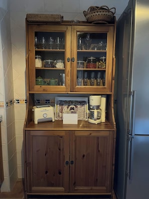 A kitchen with wooden cabinets, a toaster, a coffee maker, and a refrigerator.