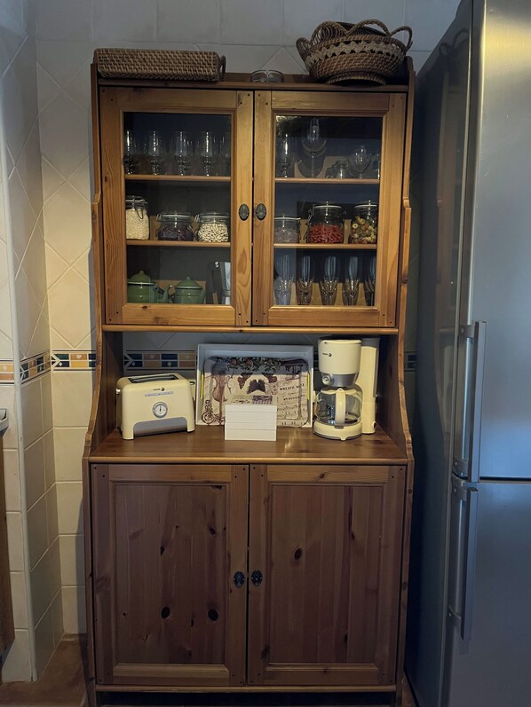 A kitchen with wooden cabinets, a toaster, a coffee maker, and a refrigerator.