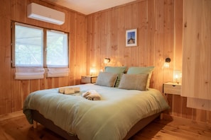 A wooden-paneled bedroom with a bed, two bedside lamps, and a picture on the wall. - Chalet du Courlis - VENDAYS MONTALIVET (VENDAYS MONTALIVET)