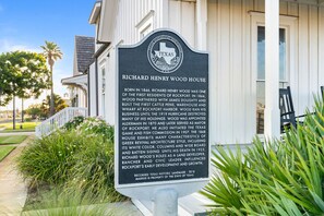 A historical marker plaque in front of a building with a porch and a white exterior. - 1868 R. H. Wood House | Historic Rockport Retreat (Rockport)