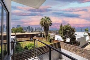 A balcony with a city skyline view, a palm tree, and a staircase. - Bay Views & Walk to Little Italy - Prime Location (San Diego)