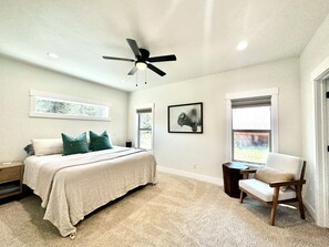 Ein Schlafzimmer mit einem Bett, einem Sessel, einem Deckenventilator und einem Fenster.