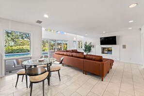 A modern living room with a glass dining table, leather sofa, and a flat-screen TV. - Renovated La Jolla Villa: Ocean Views & Pool (San Diego)