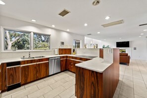 Eine moderne Küche mit Holzschränken, einem eingebauten Geschirrspüler und einem großen Fenster für natürliches Licht.