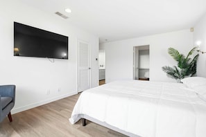 A bedroom with a bed, a TV, a chair, and a plant. - Renovated La Jolla Villa: Ocean Views & Pool (San Diego)