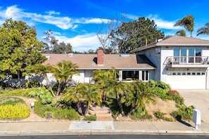 A two-story house with a garage, a covered porch, and a landscaped front yard with palm trees. - Renovated La Jolla Villa: Ocean Views & Pool (San Diego)