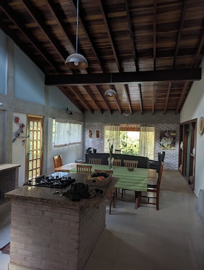 A spacious kitchen with a central island, wooden ceiling beams, and a dining area with a table and chairs. - Awesome 2-bedroom chácara in peaceful Delfim Moreira getaway (Delfim Moreira)