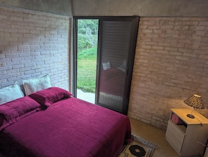 A bedroom with a bed, a nightstand, and a sliding glass door leading to a balcony. - Awesome 2-bedroom chácara in peaceful Delfim Moreira getaway (Delfim Moreira)