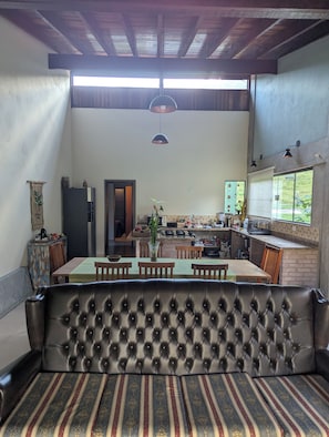 A dining area with a sofa, a table, and chairs. There is a kitchen area with a counter and various appliances. - Awesome 2-bedroom chácara in peaceful Delfim Moreira getaway (Delfim Moreira)