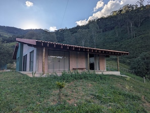 A single-story building with a sloped roof, large windows, and a wooden porch. - Awesome 2-bedroom chácara in peaceful Delfim Moreira getaway (Delfim Moreira)