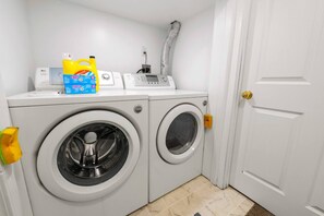 A laundry room with two front-loading washing machines, a dryer, and a water heater. - 2BR Suite - 4 Min Walk to WEM - Free Parking (Edmonton)