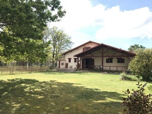 A two-story house with a porch, a fenced yard, and trees. - Villa Bécassière - VENDAYS MONTALIVET (VENDAYS MONTALIVET)