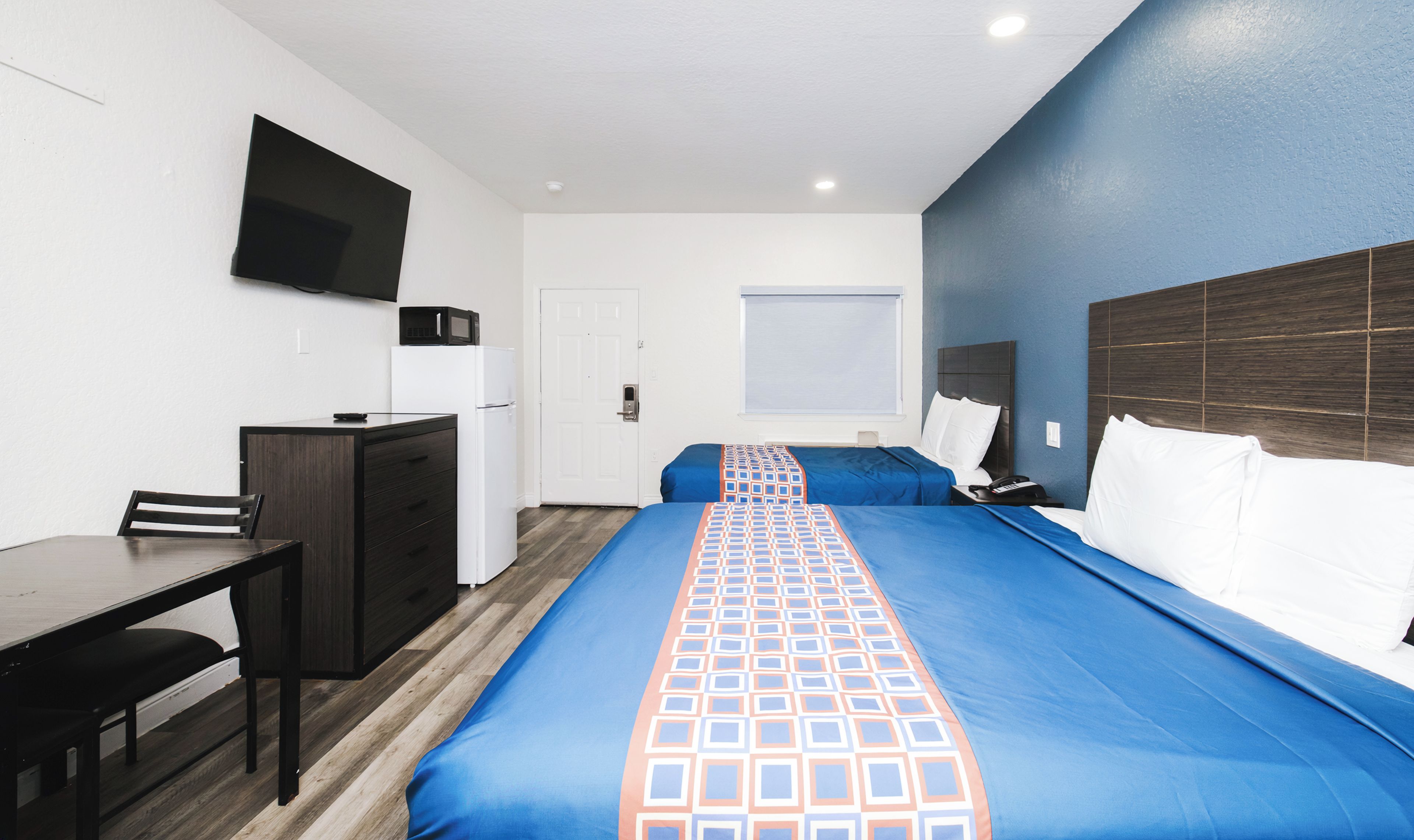 Une chambre d’hôtel avec un lit, un bureau, une chaise, une télévision et une fenêtre.