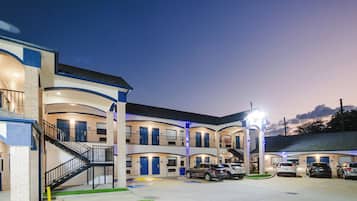 Un motel à plusieurs étages doté d’une cour intérieure, d’un parking extérieur et d’un escalier menant aux niveaux supérieurs.