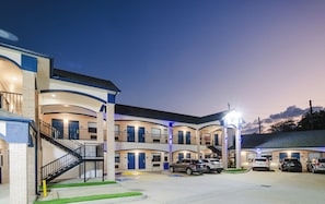 A multi-story motel with a central courtyard, outdoor parking, and a staircase leading to the upper levels. - Viva Inn (Houston)