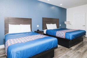 A hotel room with two beds, each with a headboard, a bedside table, and a telephone. - Viva Inn (Houston)