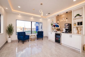 A modern hotel room with a seating area, a kitchenette, and a large window offering a view of the outside. - Viva Inn (Houston)