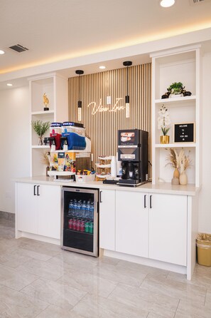 A kitchenette with a coffee machine, a water dispenser, and a refrigerator. - Viva Inn (Houston)
