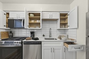 A modern kitchen with white cabinets, a stove, dishwasher, and a microwave. - Cozy Stylish Apt in Omaha`s Medical District! (Omaha)