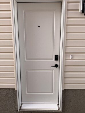 A white door with a keypad lock and a doorbell. - Cozy Private 1-Bedroom Suite |  Free Parking & Wi-Fi (Regina)