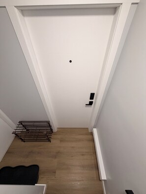 Una habitación con una puerta blanca, suelo de madera y un radiador.