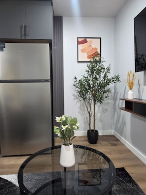 Eine moderne Küche mit einem Edelstahlkühlschrank, einem Blumentopf und einem Glastisch.