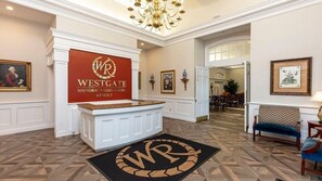 A reception area with a sign for Westgate Historic Williamsburg Resort, a chandelier, framed artwork, and a patterned carpet. - Historic Escape – 1BR Villa at Westgate Williamsburg (Williamsburg)