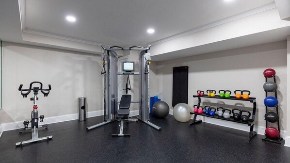 A gym with a variety of exercise equipment including a stationary bike, a weight machine, and a rack of kettlebells. - Historic Escape – 1BR Villa at Westgate Williamsburg (Williamsburg)