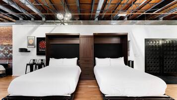Une chambre d’hôtel avec deux lits, un mur en briques et un plafond avec des poutres apparentes.