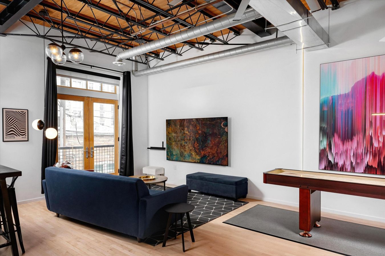 Un salon moderne avec un canapé bleu, une table basse et un grand tableau abstrait.