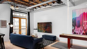 Un salon moderne avec un canapé bleu, une table basse et un grand tableau abstrait.