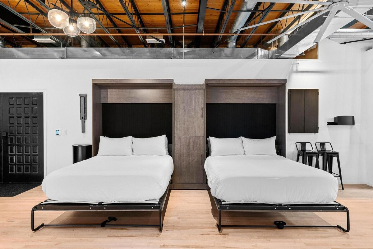 Een moderne slaapkamer met twee bedden, een houten plafond en een zwarte deur.