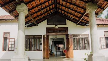 A traditional building with a tiled roof, wooden columns, and a central doorway.