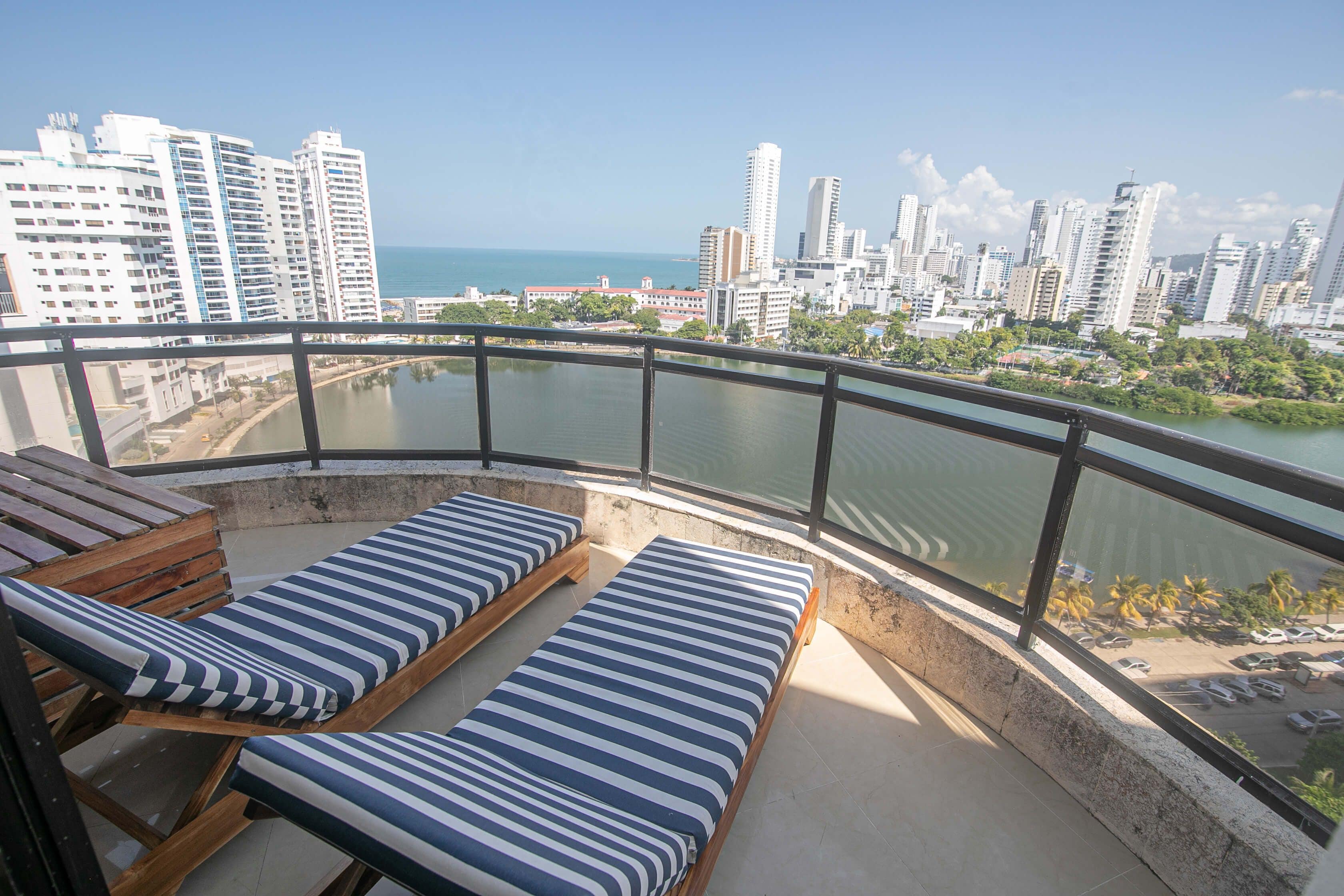 A balcony with two lounge chairs and a view of a cityscape and water.