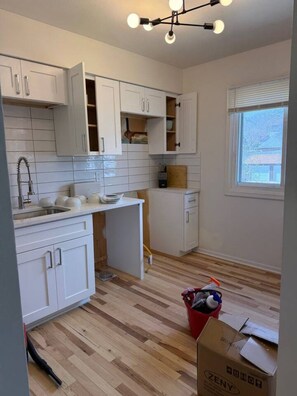 A kitchen with white cabinets, a wooden countertop, and a window. - Cozy Stylish Apt in Omaha`s Medical District! (Omaha)