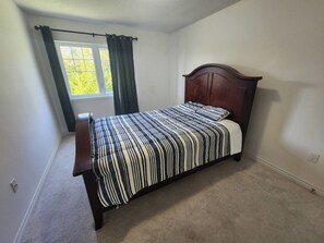 A bedroom with a single bed, a window with curtains, and a carpeted floor. - Spacious 4-bedroom 4 Bathroom House Near Wasaga Beach (Wasaga Beach)