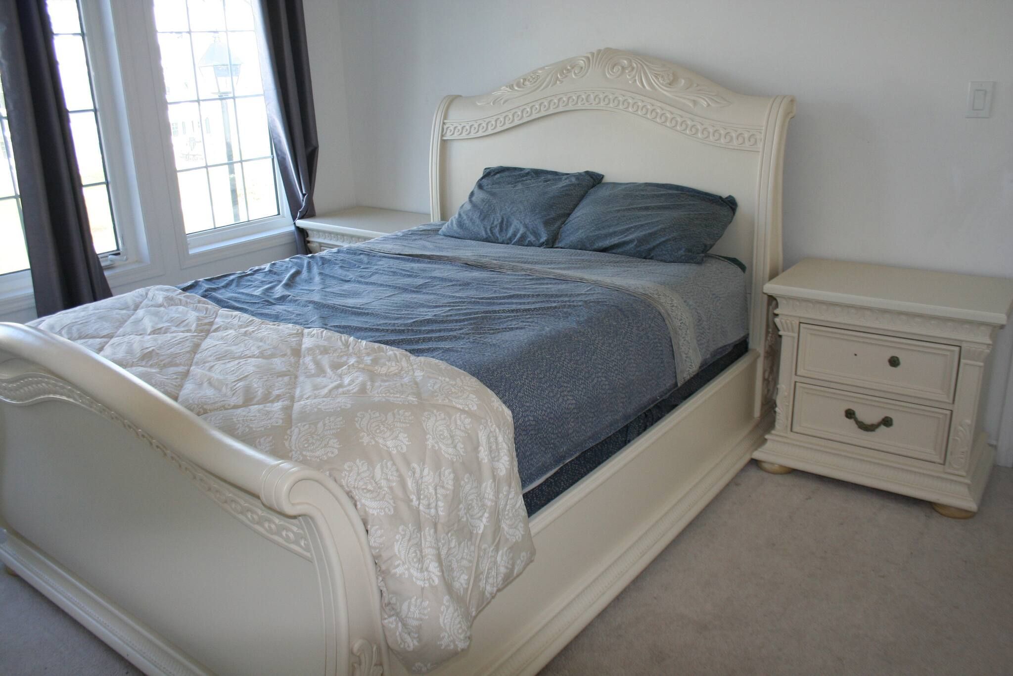 A bed with a white headboard and a bedside table with a drawer.